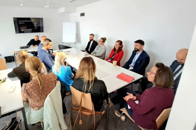 Sala warsztatowa, grupa uczestników przy stołach ustawionych w podkowę
